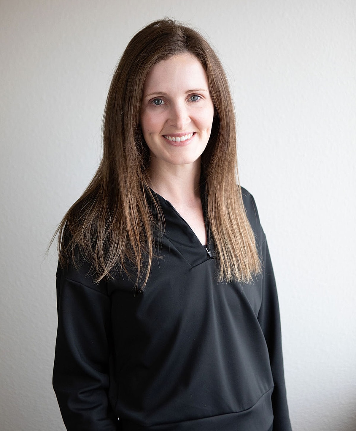 Smiling woman in black top against gray background