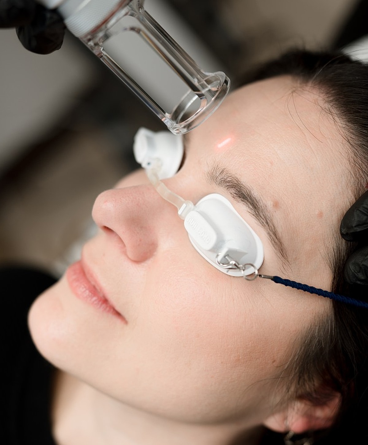 Facial treatment in progress with goggles and device.