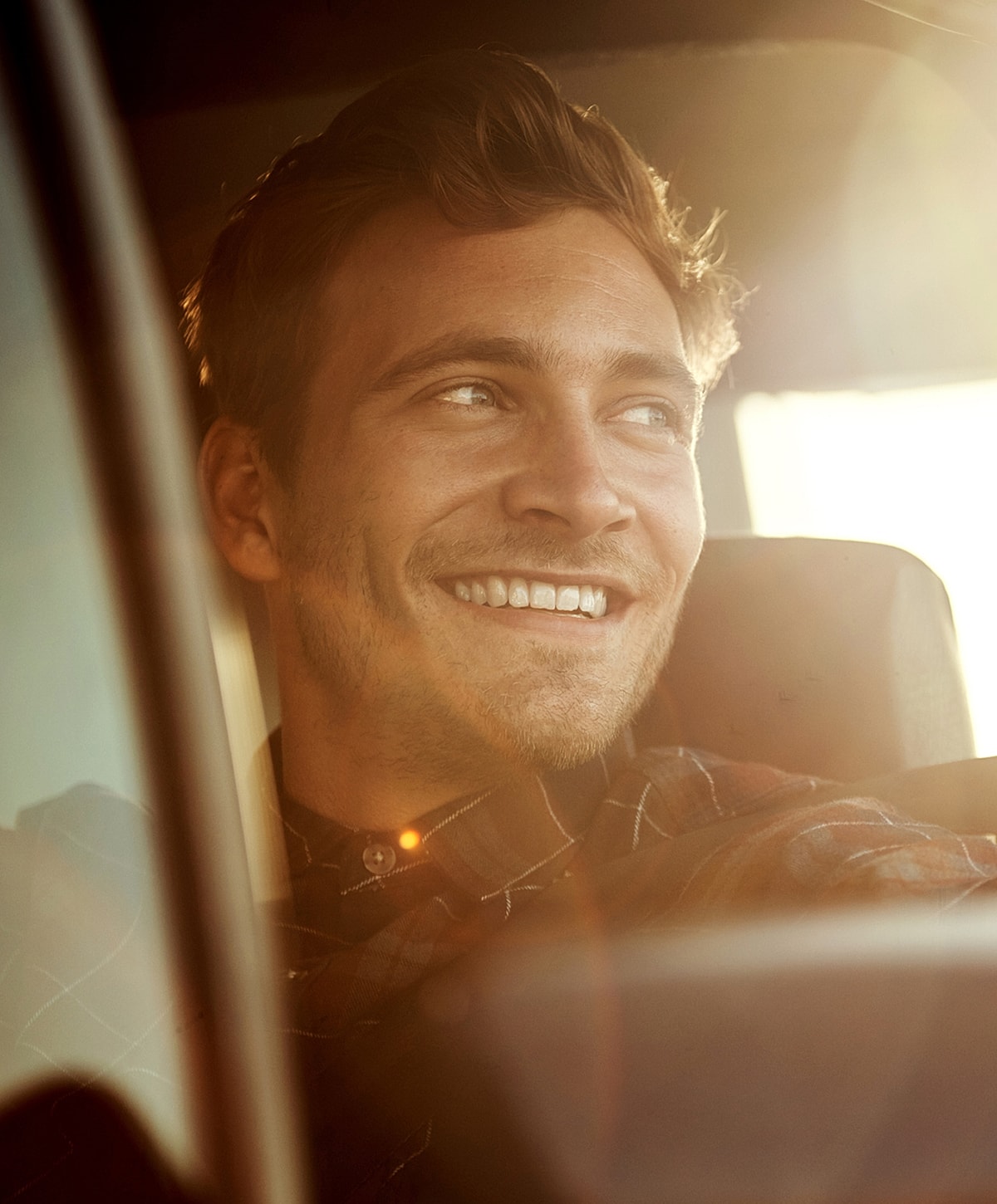 Smiling man in car during sunset.