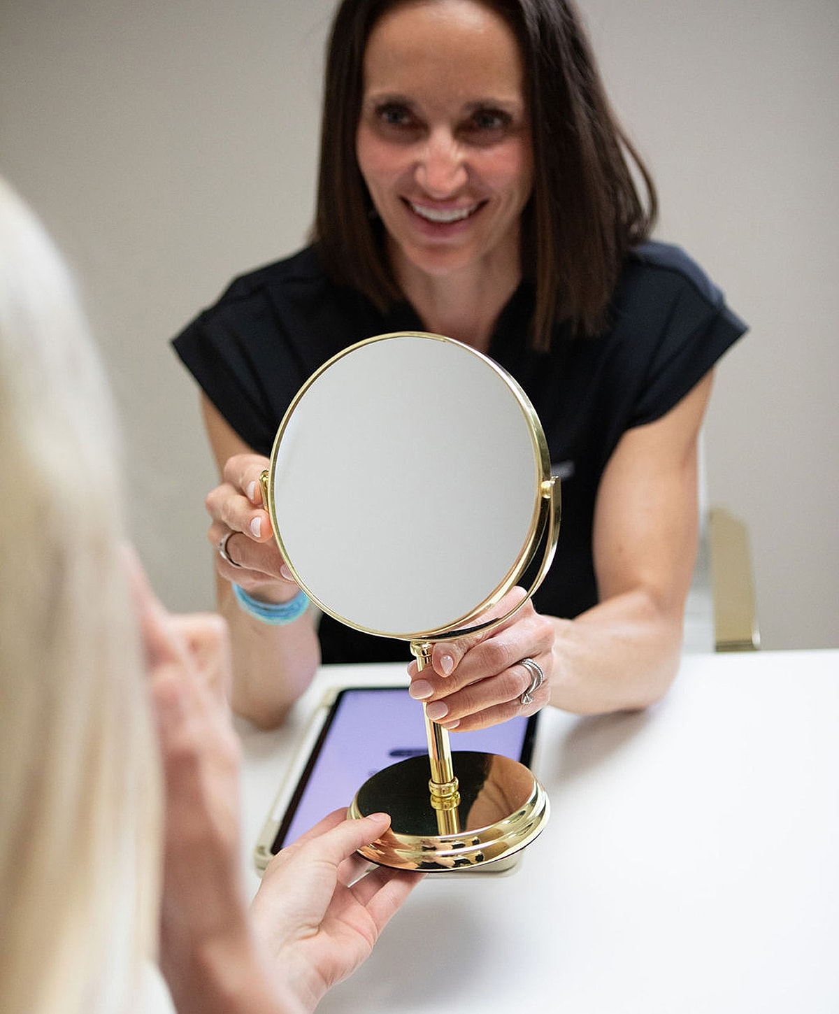 Person handing mirror to another individual.
