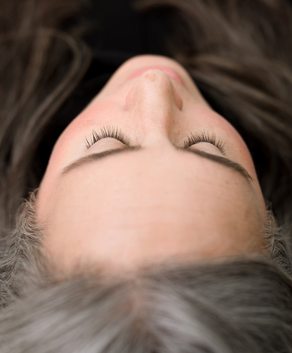 Woman lying down with eyes closed, relaxed.