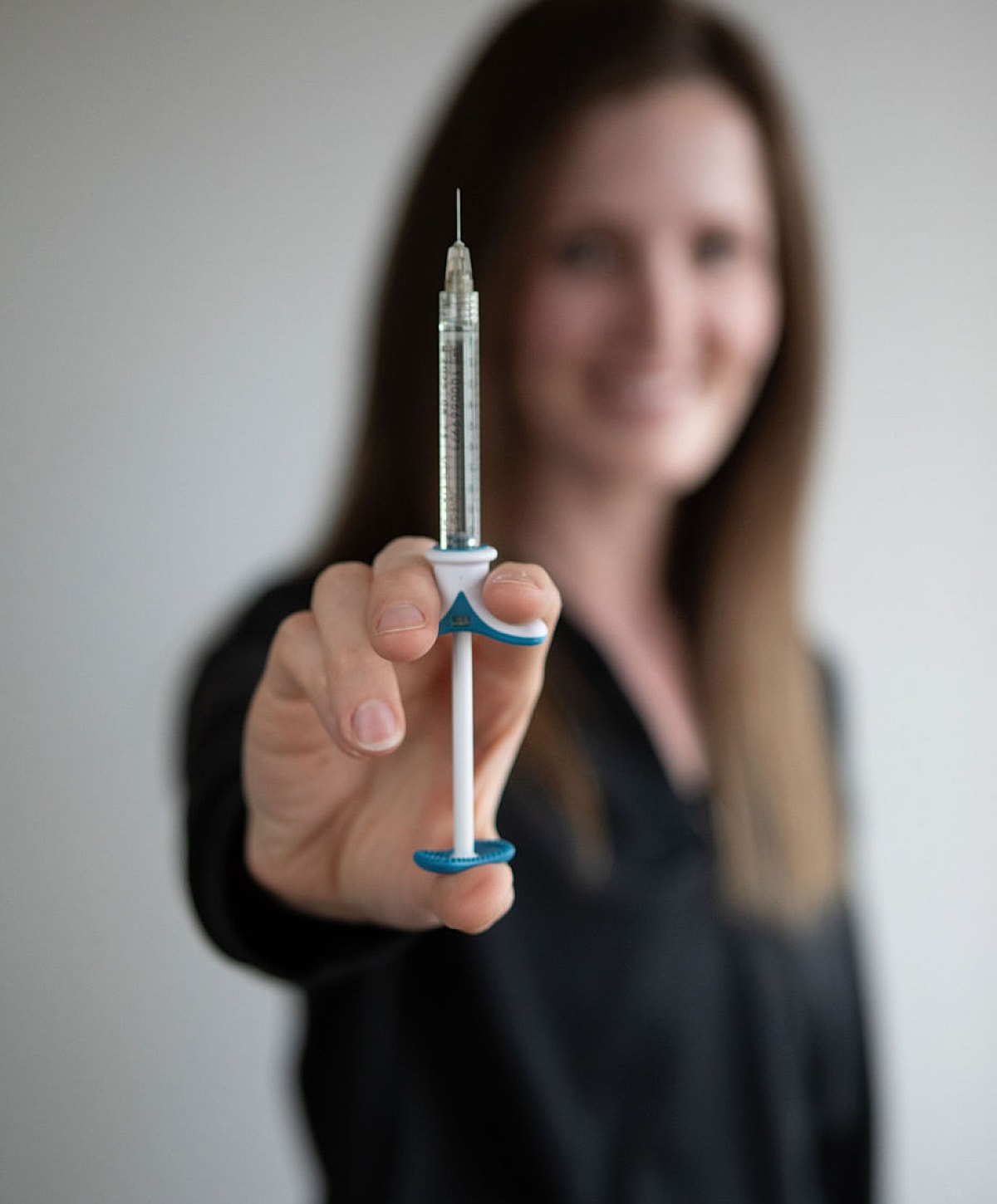 Person holding a syringe with a smile.