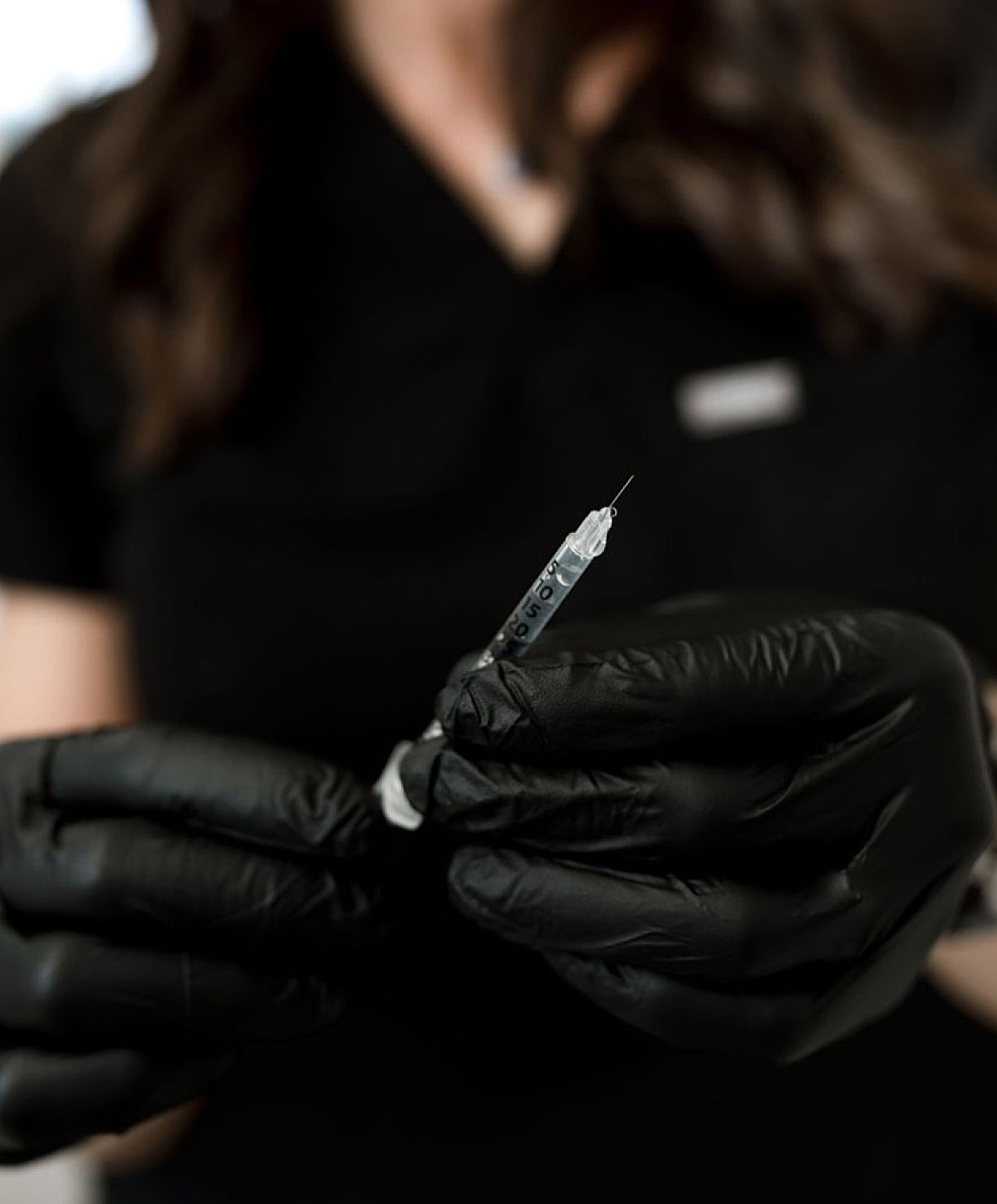 Gloved hands holding a syringe for vaccination.