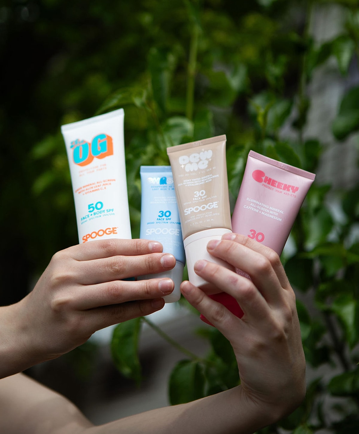 Assorted sunscreen products in hands outdoors.