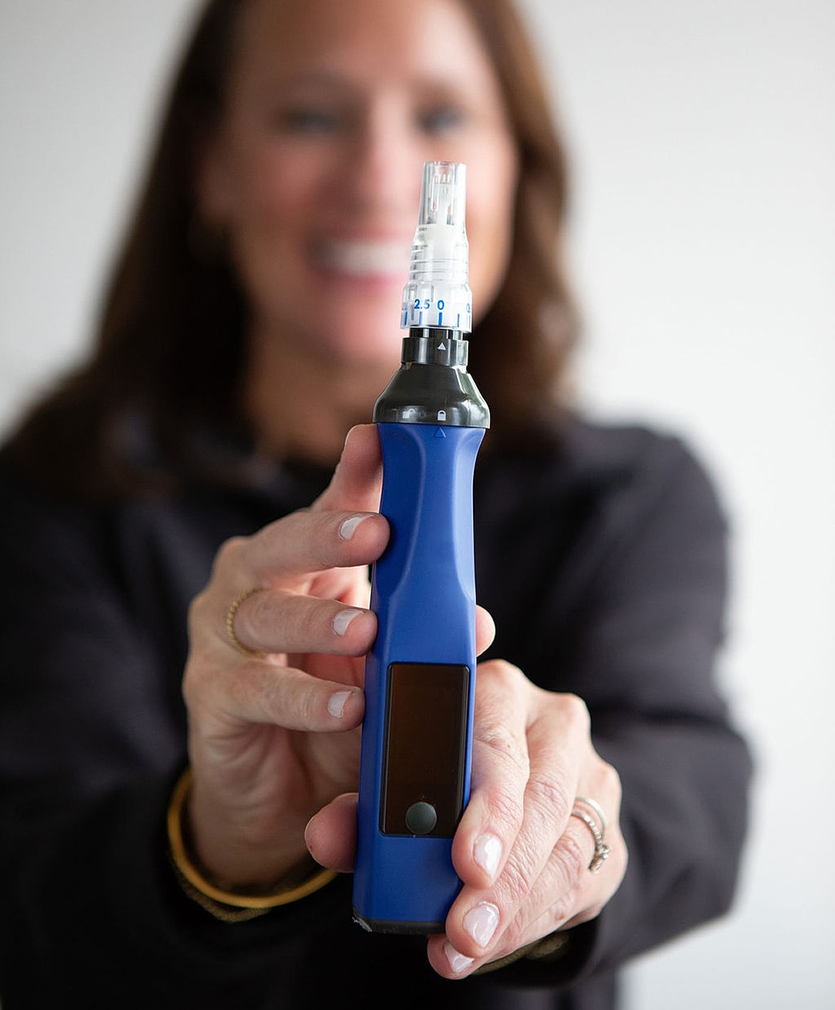 Person holding a blue microneedling device.