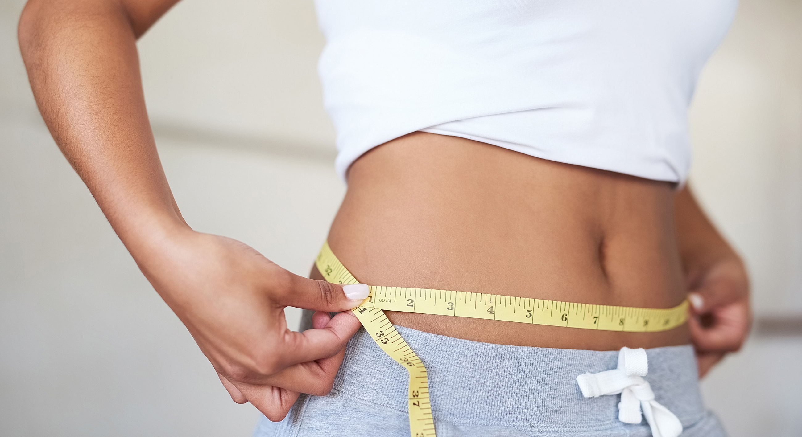 Measuring waist with tape measure for fitness.